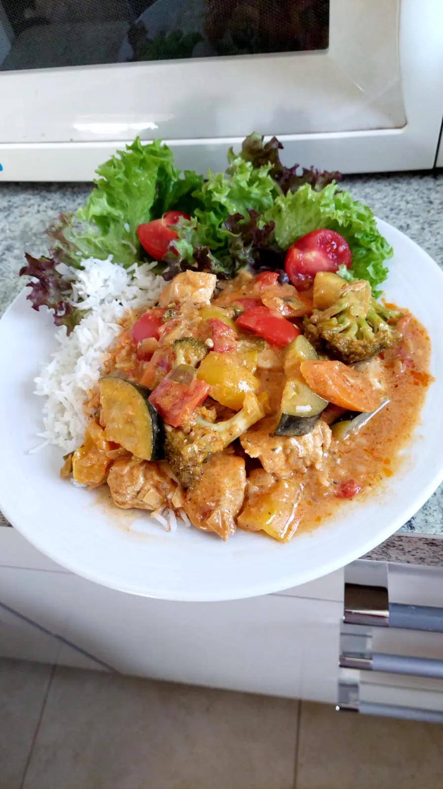 A plate of curry with rice and fresh salad