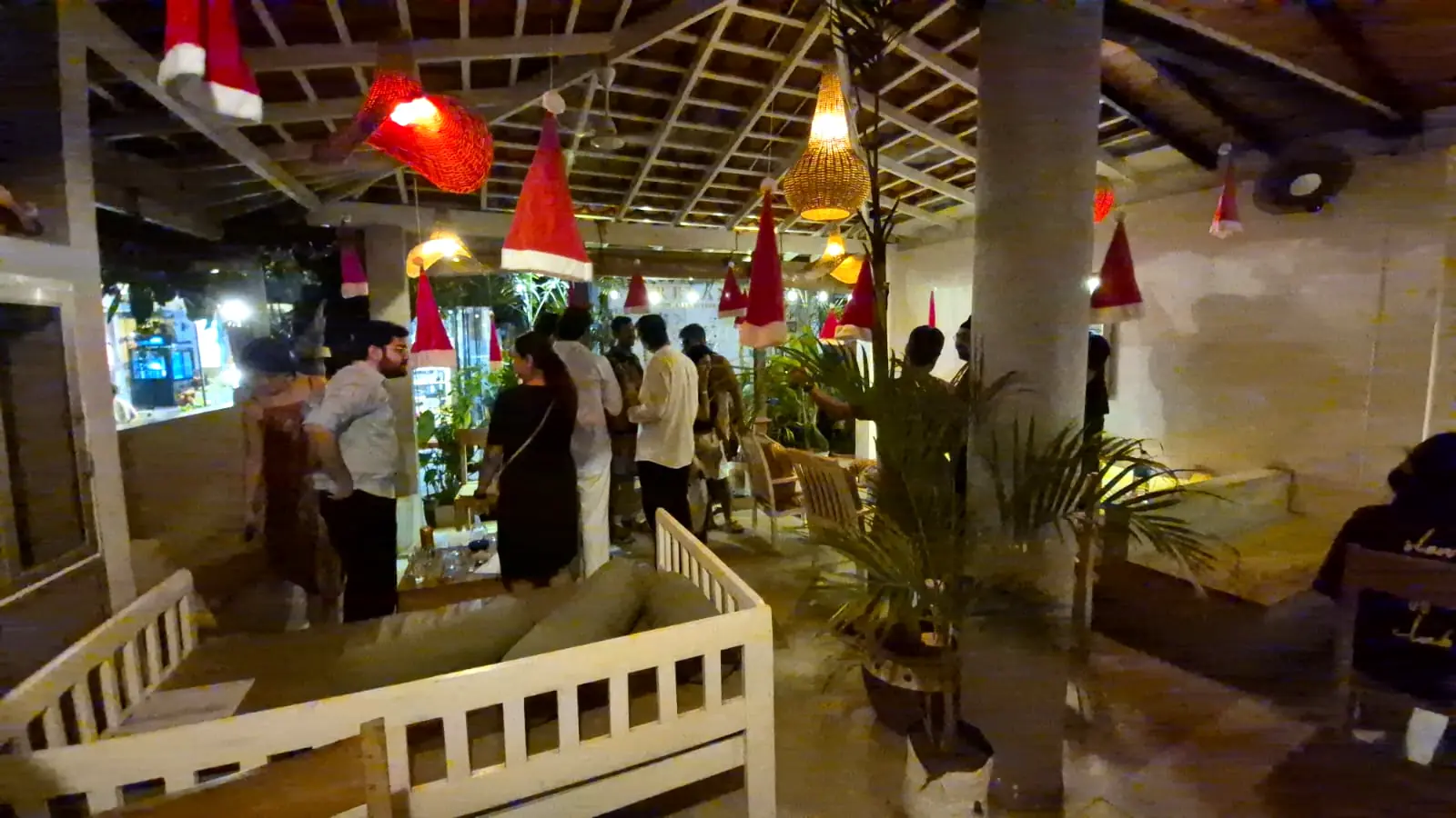 The front terrace of Pink Elephant at night, with white garden benches and potted palms