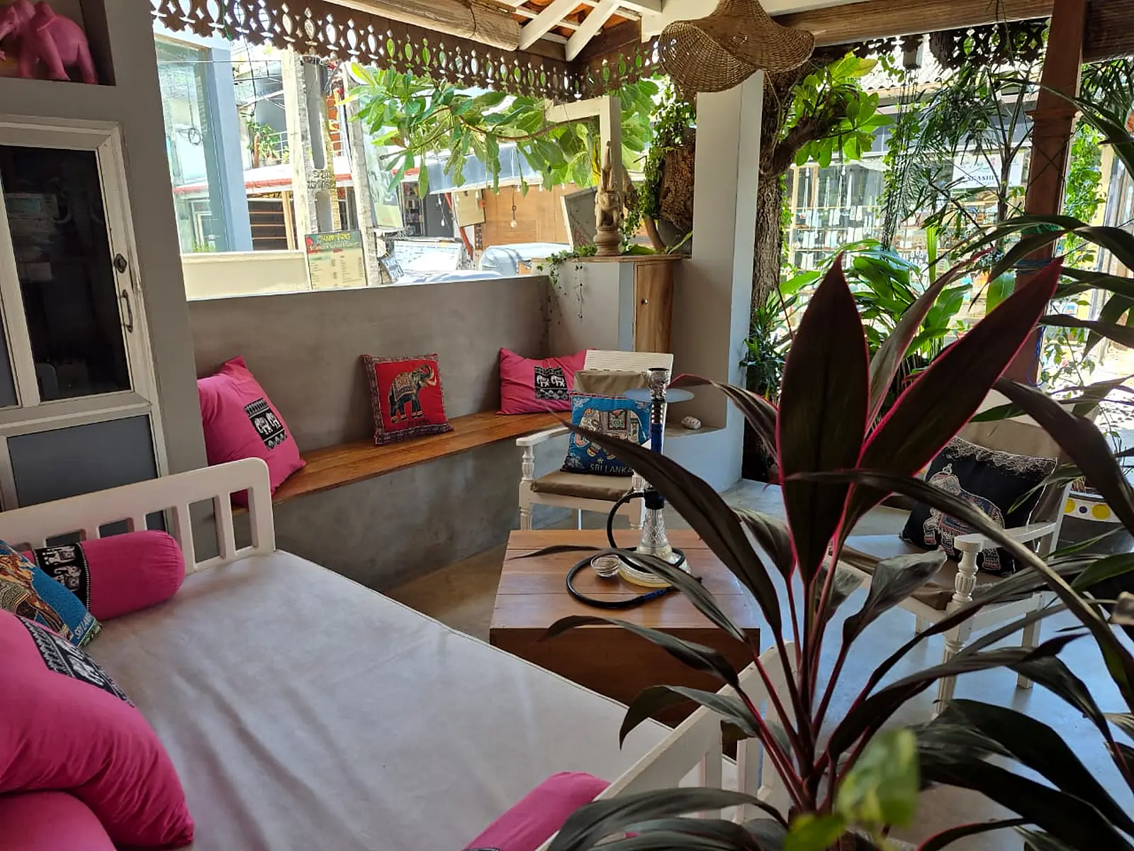 The lounge corner at Pink Elephant with a white daybed, pink cushions and tropical plants