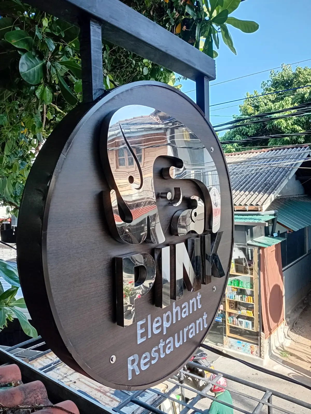 The round Pink Elephant Restaurant sign hanging over Yaddehimulla Road in Unawatuna